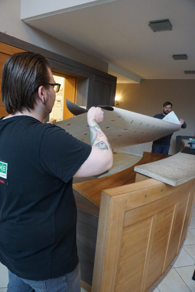 Fotoreklame employee applies furniture film to a hotel counter.