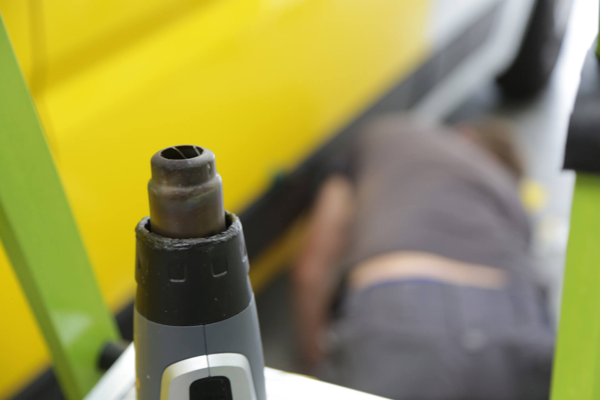 Heißluftföhn steht auf Tisch. Im Hintergrund arbeitet Fotoreklame Mitarbeiter an Fahrzeug